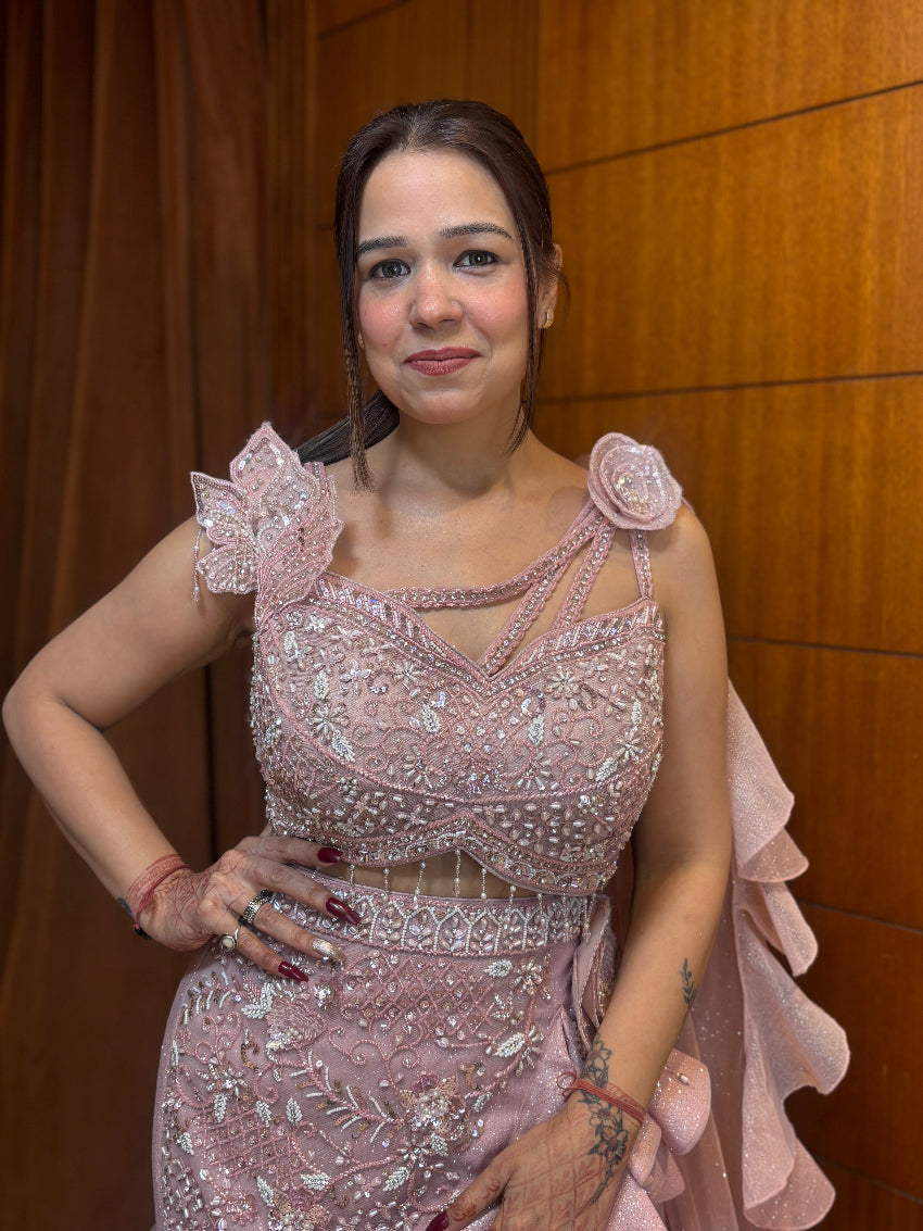 Woman in a pink beaded dress posing against a wooden wall.