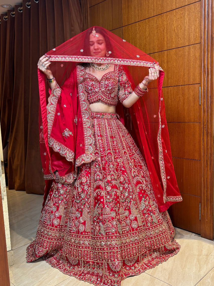 Woman in a traditional red and gold embroidered outfit with a matching dupatta.