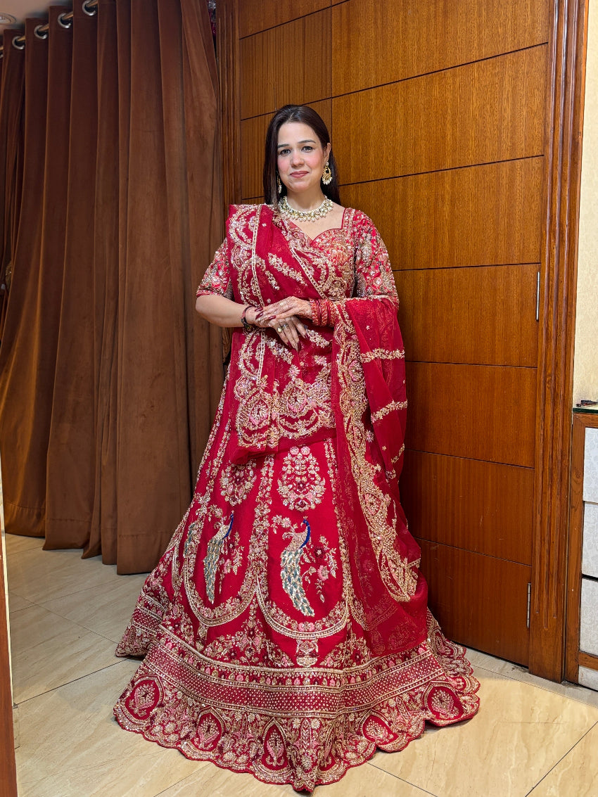 Woman in a red embroidered traditional outfit standing against a wooden panel background