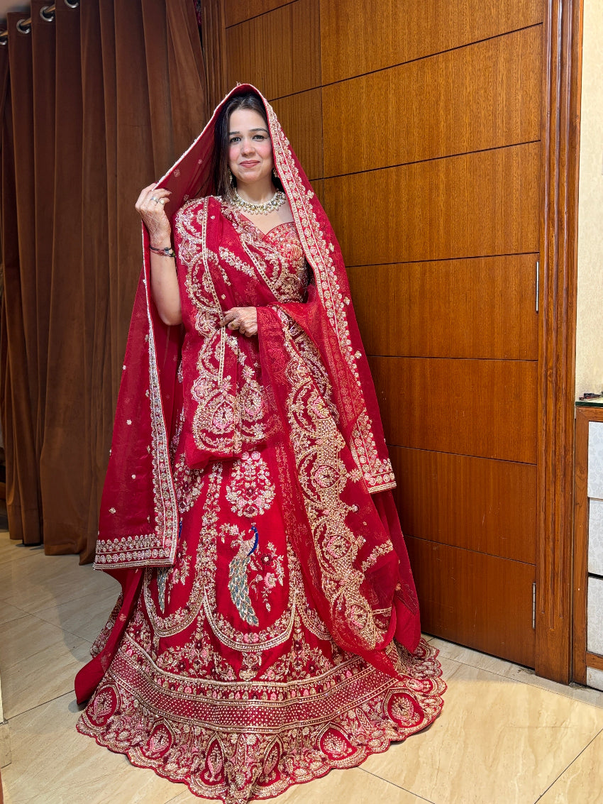 Woman in a red embroidered traditional outfit standing indoors with wooden paneling.