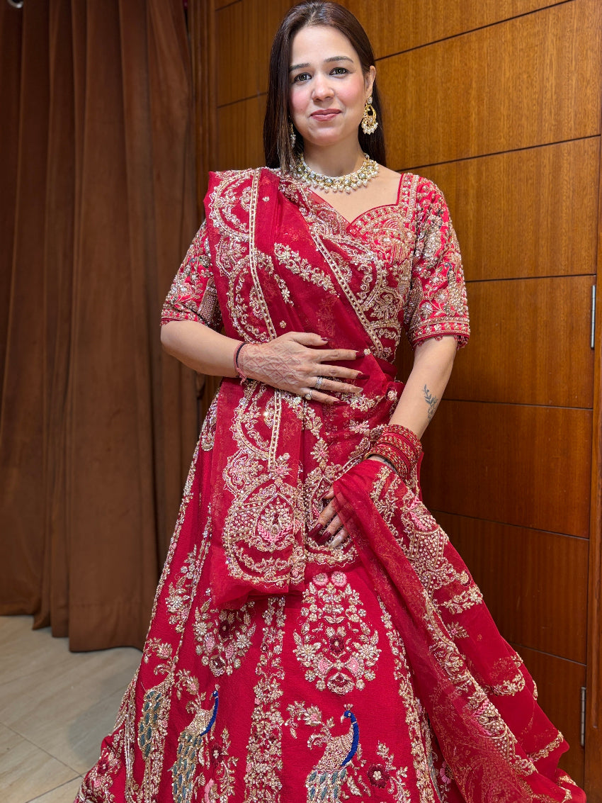 Woman in a red embroidered traditional outfit standing against a wooden panel background