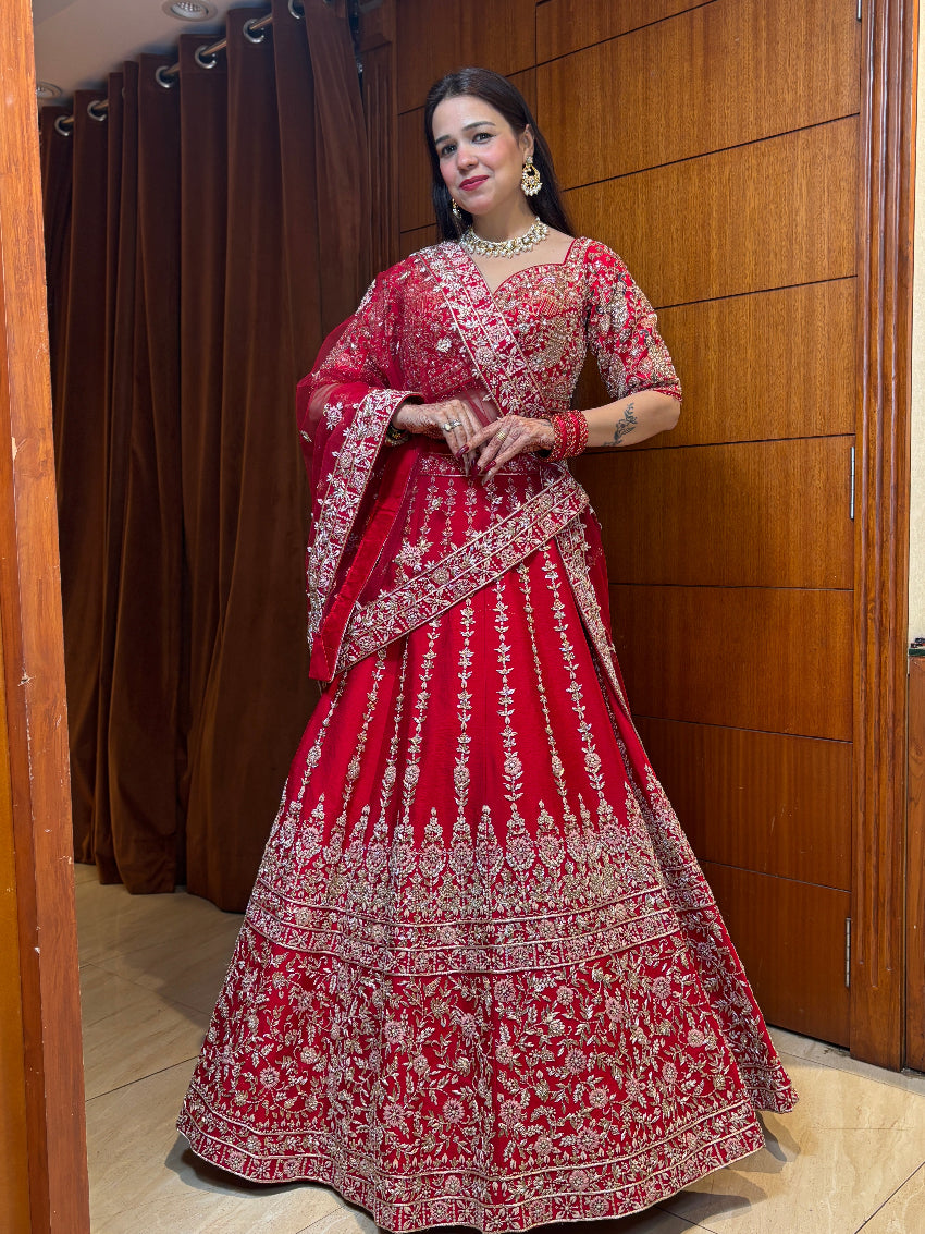 Woman in a red and white traditional outfit standing against a wooden panel background