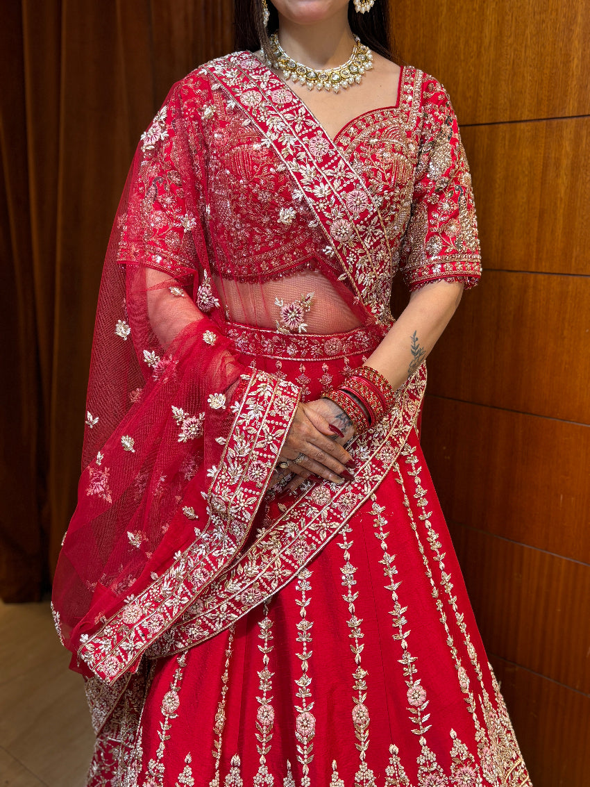 Red embroidered traditional outfit with a matching dupatta against a wooden background