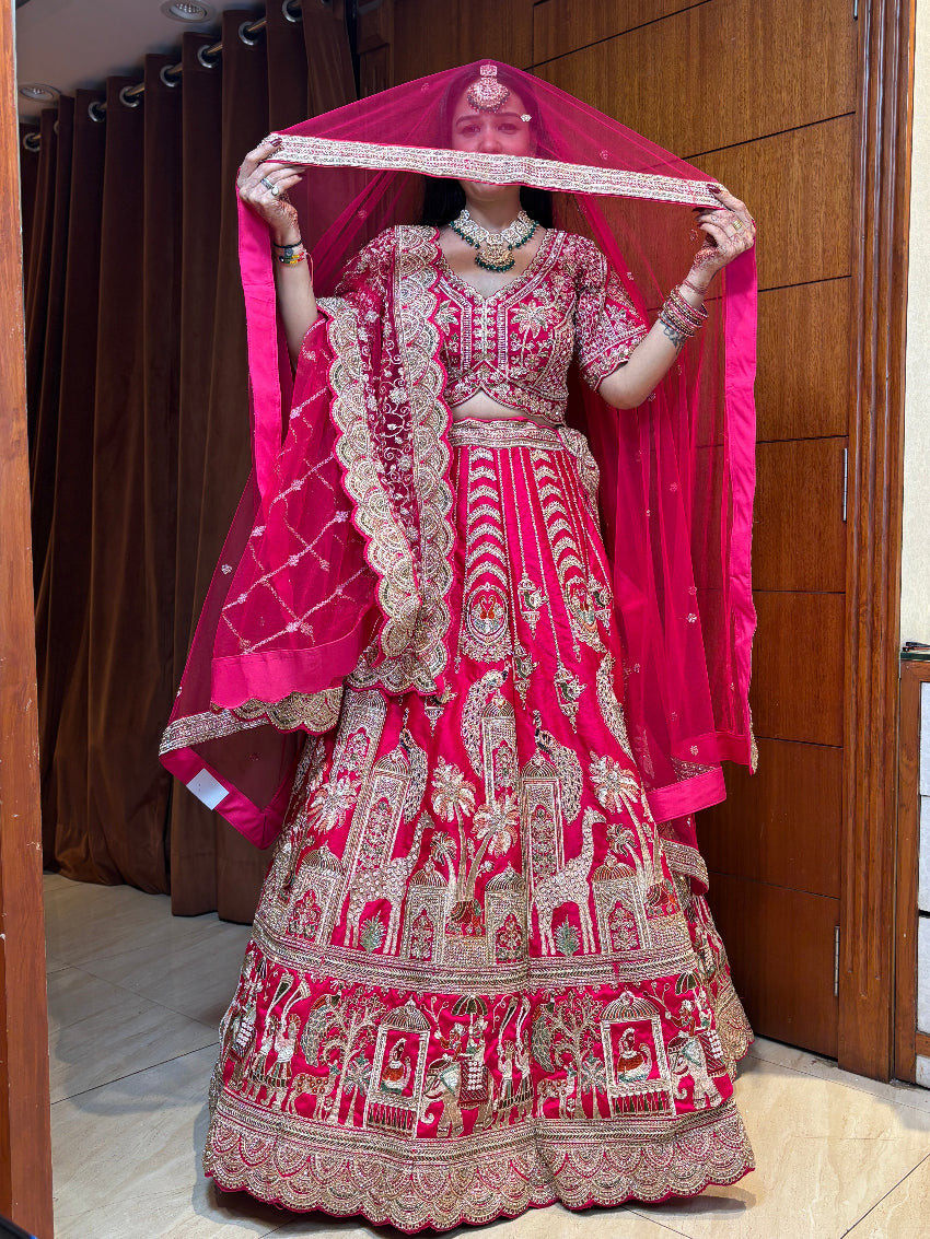 Woman in a traditional pink and red embroidered outfit holding a matching dupatta.