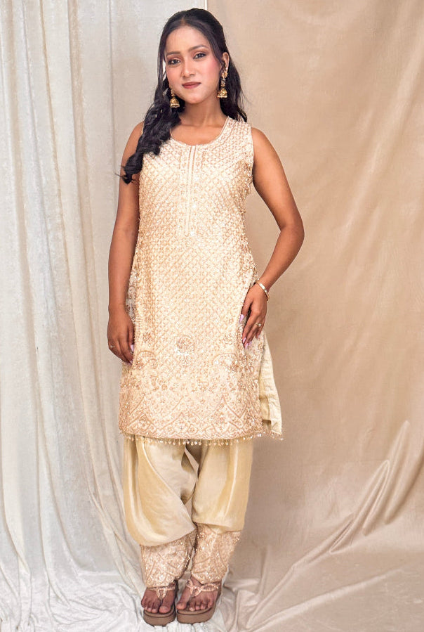 Woman wearing a beige traditional outfit against a plain background