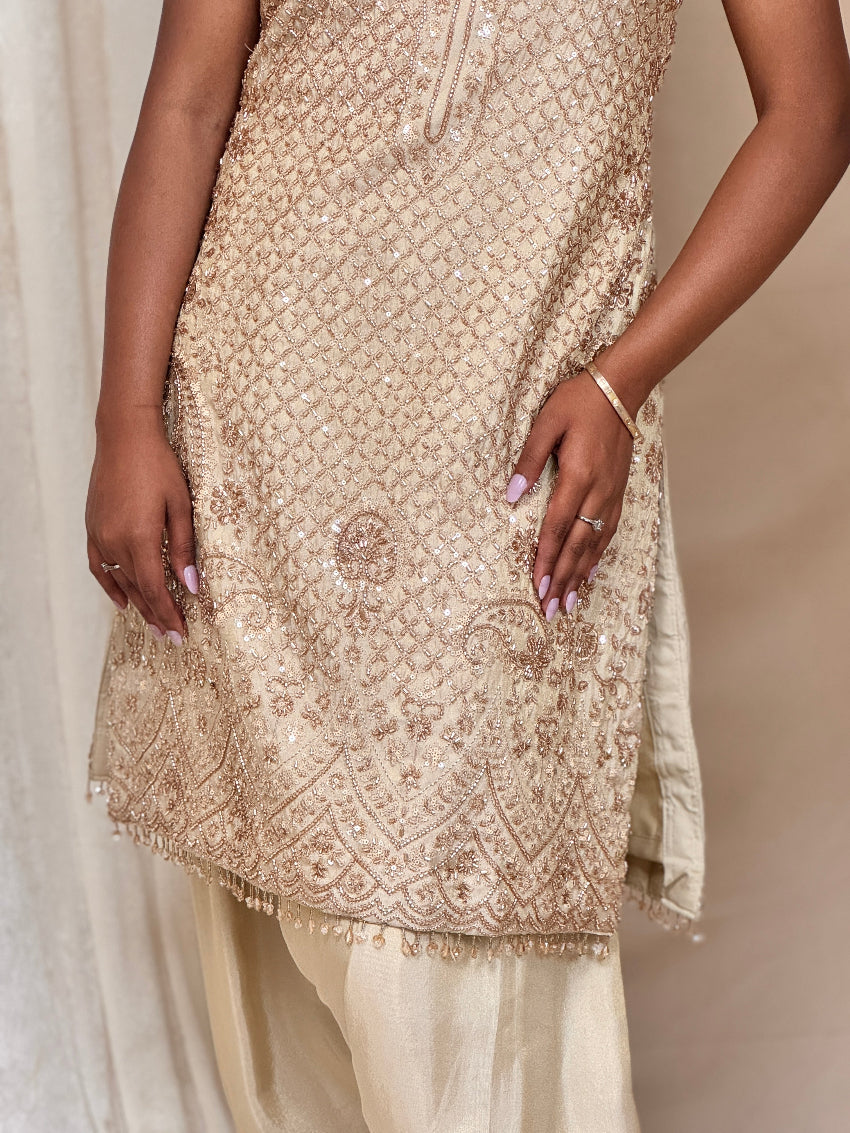 Beige embroidered kurta with white pants on a neutral background