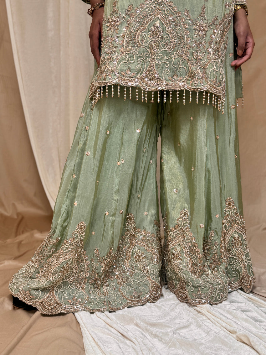 Green embroidered traditional outfit on a beige background