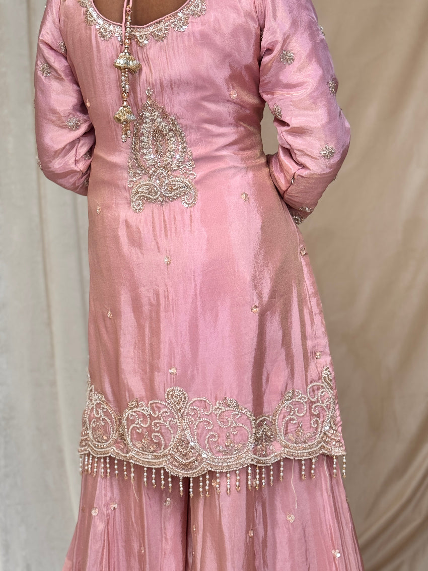 Pink traditional outfit with intricate embroidery on a plain background
