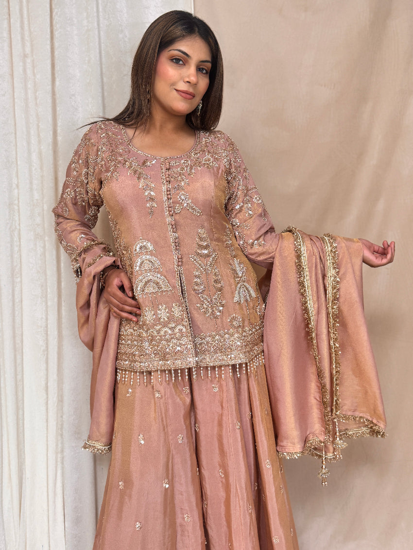 Woman wearing a traditional embroidered pink outfit with a beige background