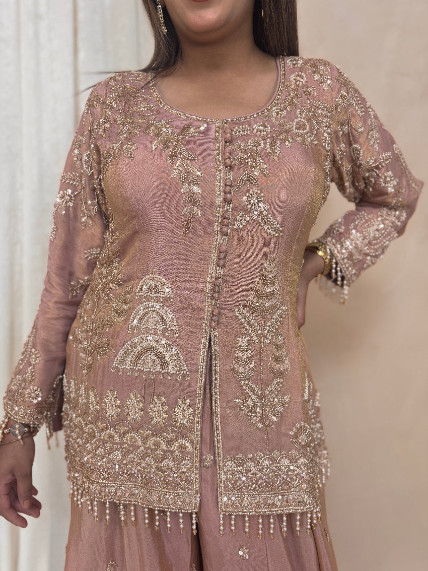 Pink embroidered traditional outfit with gold details on a neutral background