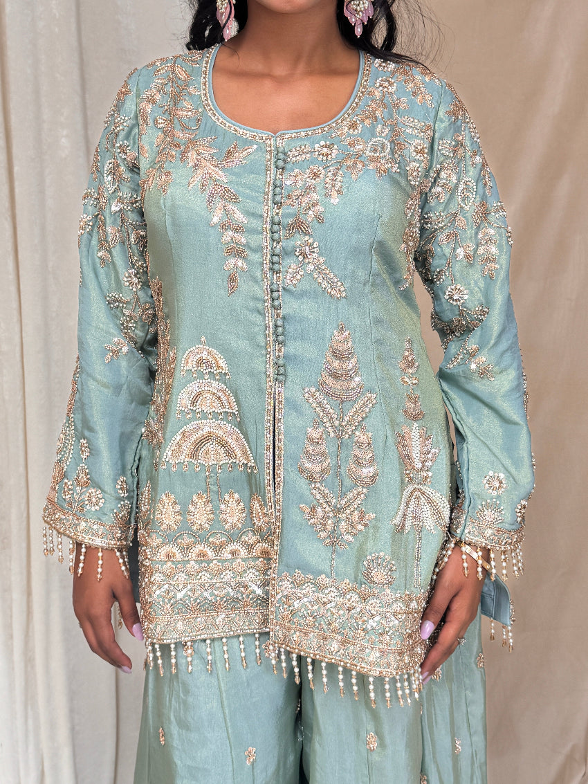 Light blue embroidered traditional outfit with gold details on a neutral background