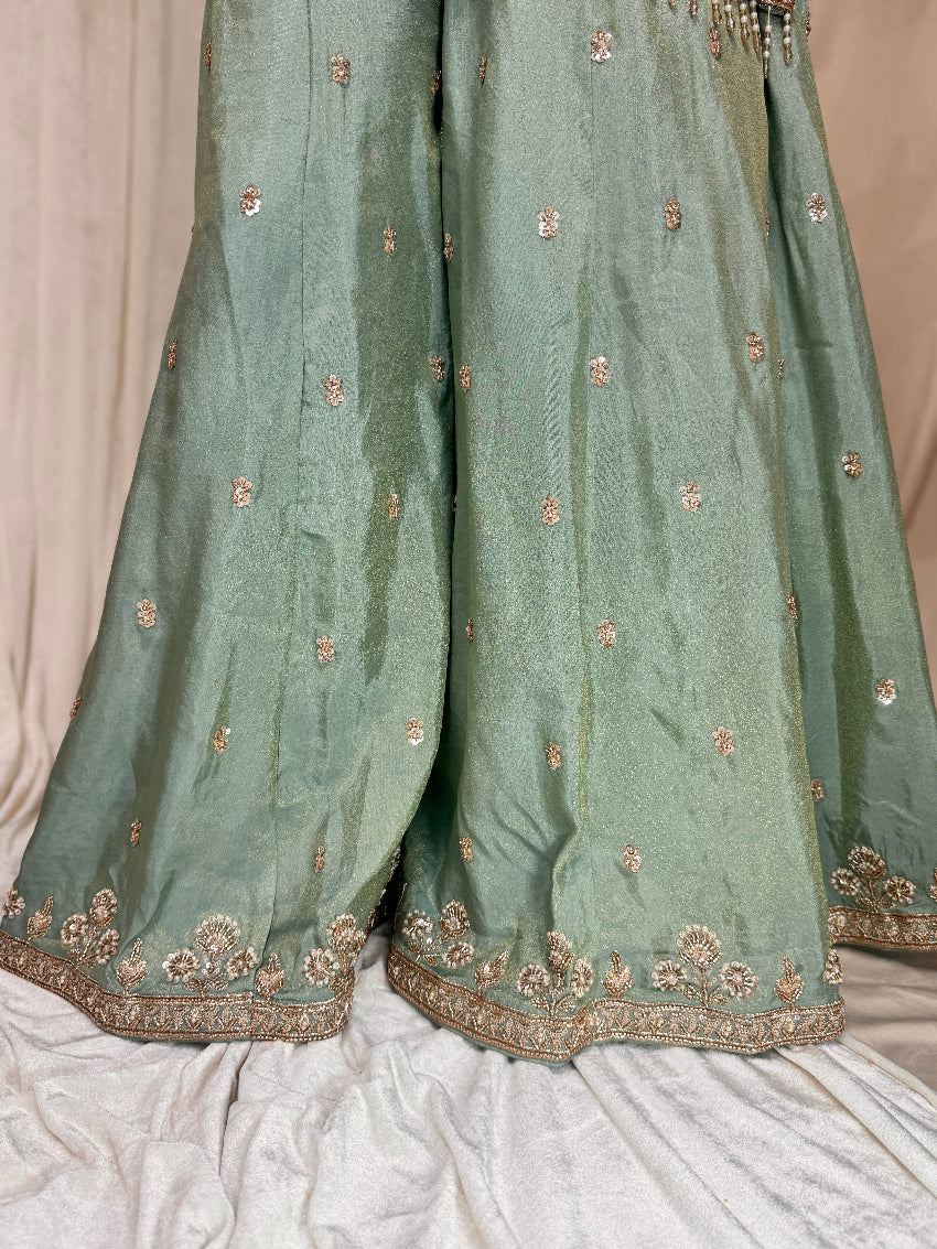 Green traditional outfit with intricate gold embroidery on a light background