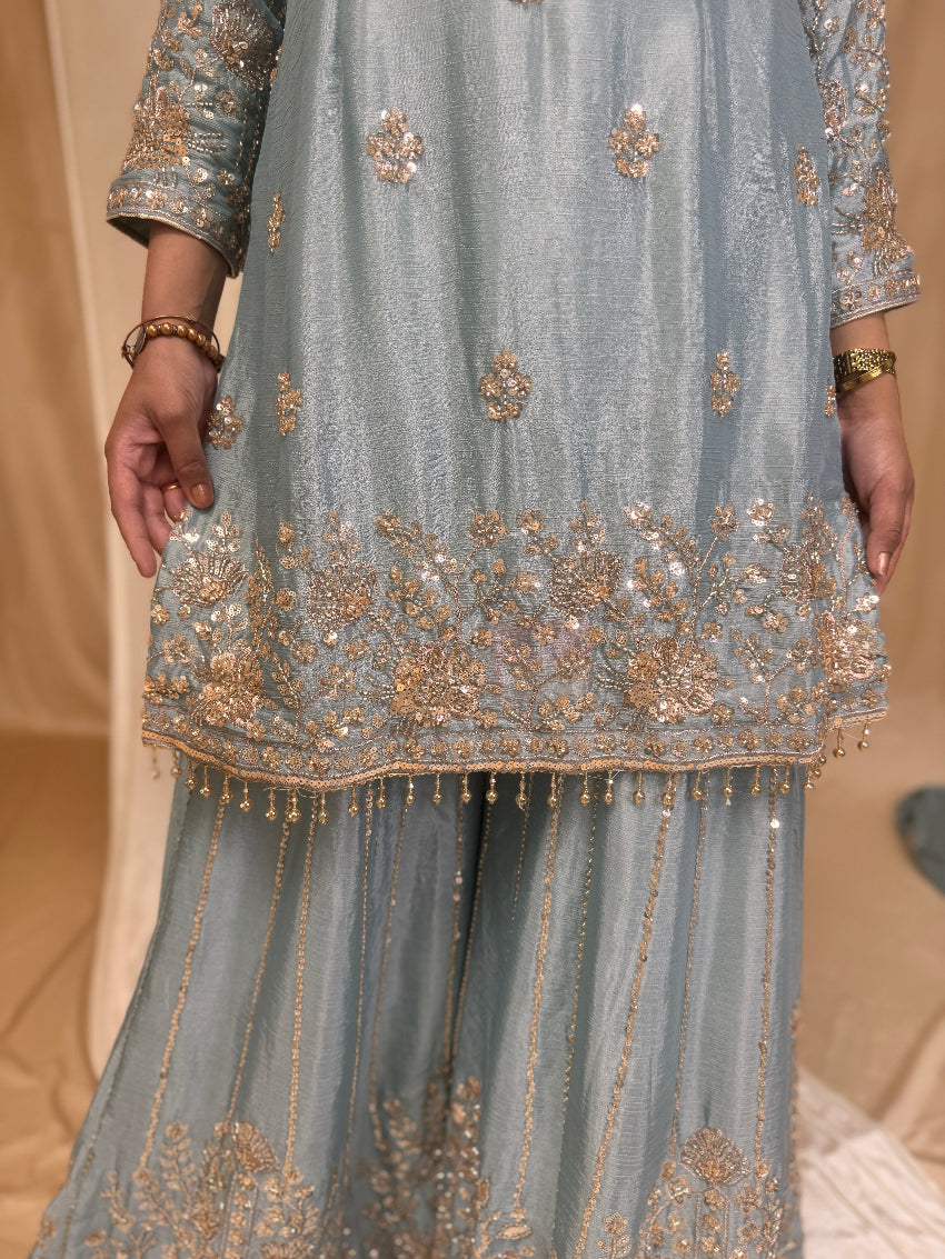 Traditional embroidered outfit with gold details on a beige background