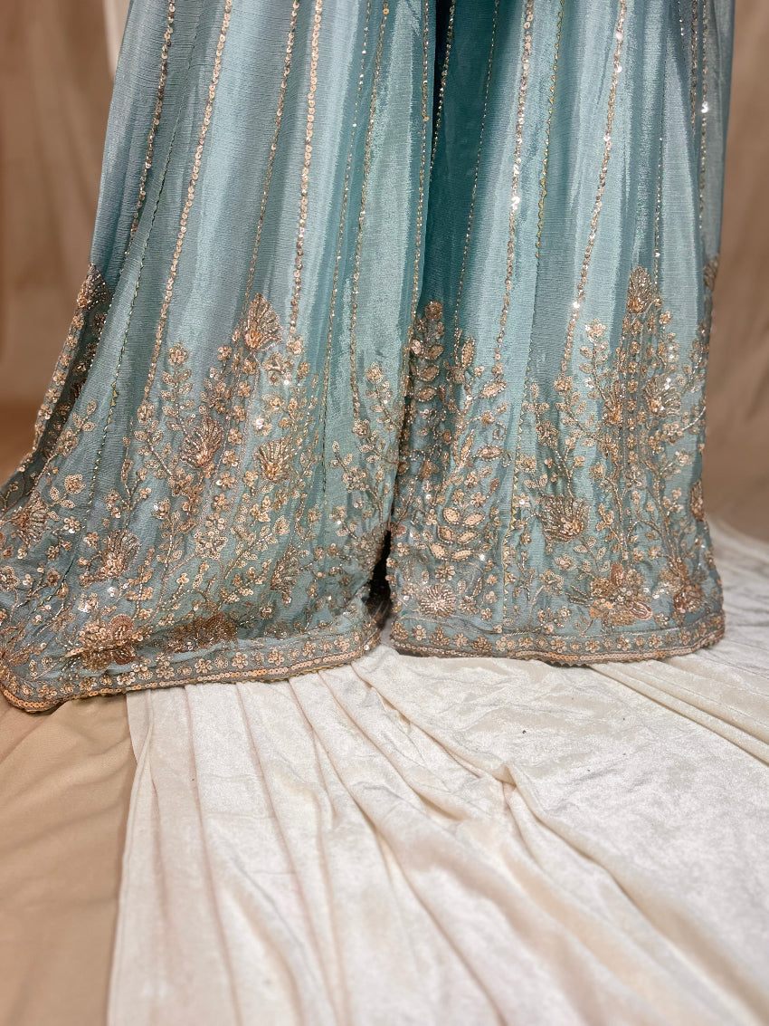 Close-up of a blue embroidered fabric with gold details on a beige background