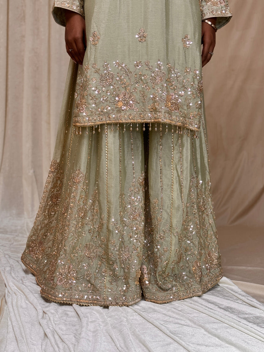 Traditional outfit with embroidered top and pants on a neutral background