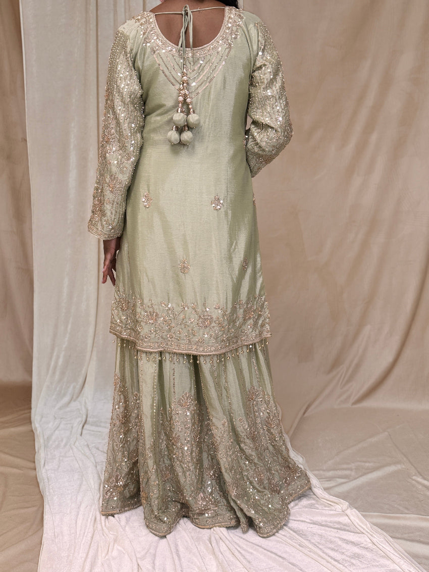 Light green embroidered traditional outfit on a neutral background