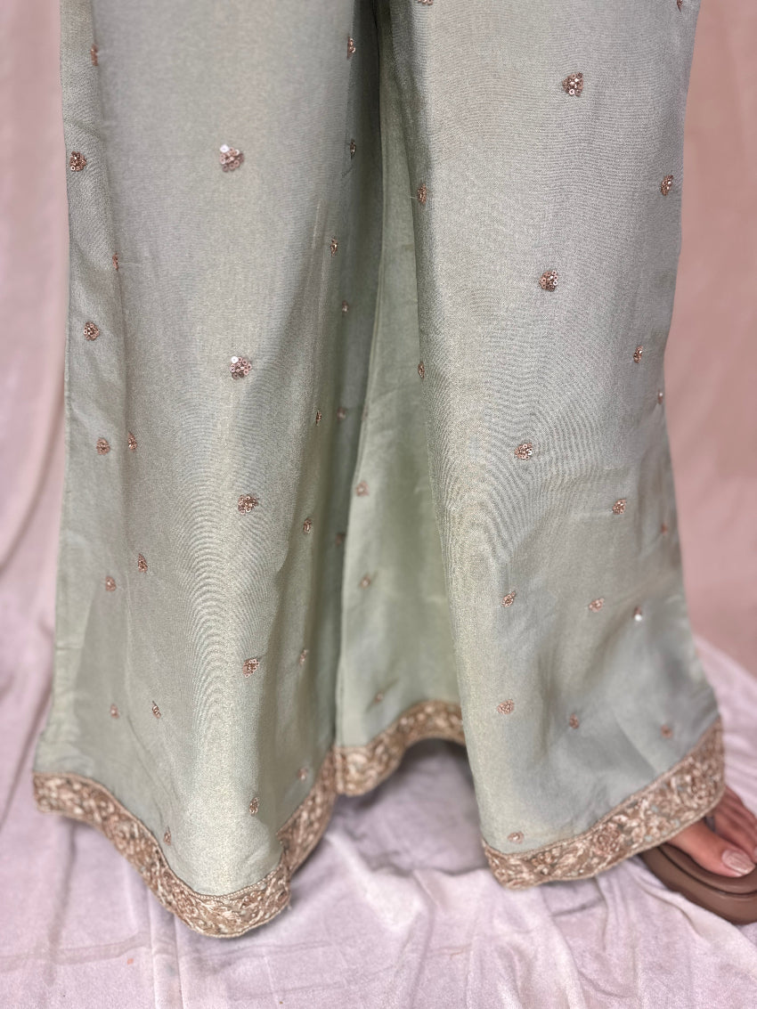 Light green fabric with gold embroidery on a neutral background