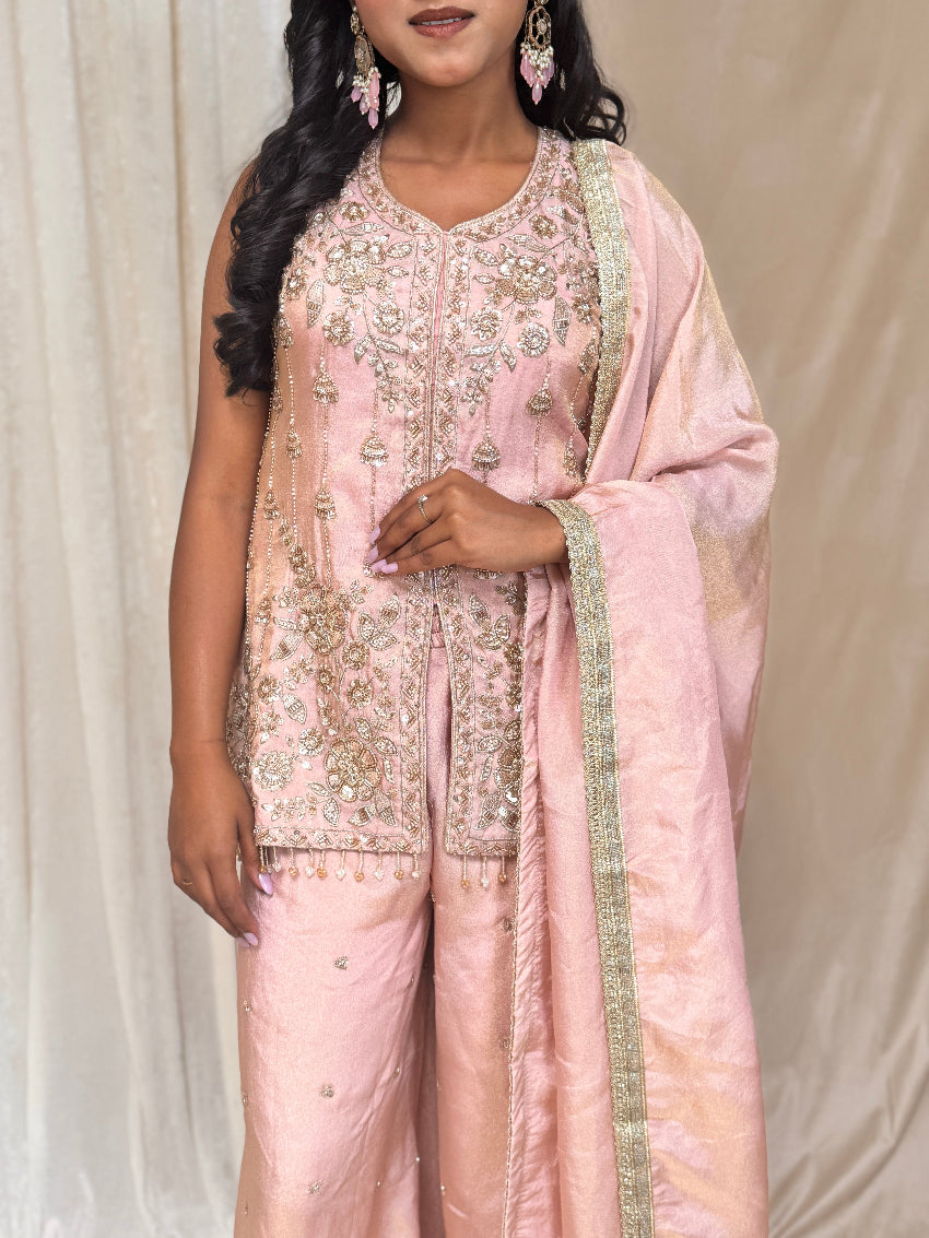 Woman wearing a pink embroidered traditional outfit against a neutral background