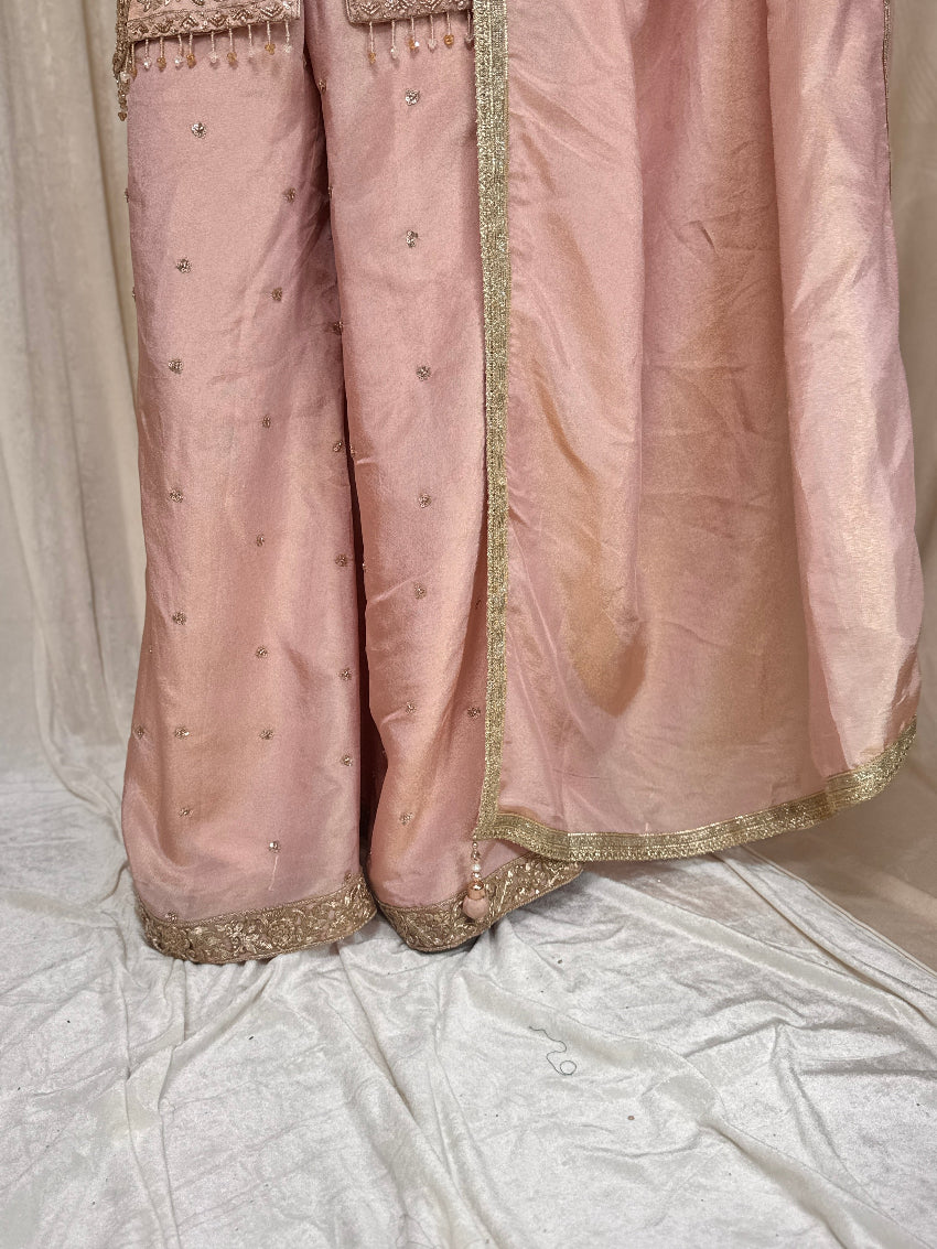 Pink traditional outfit with gold embroidery on a light background
