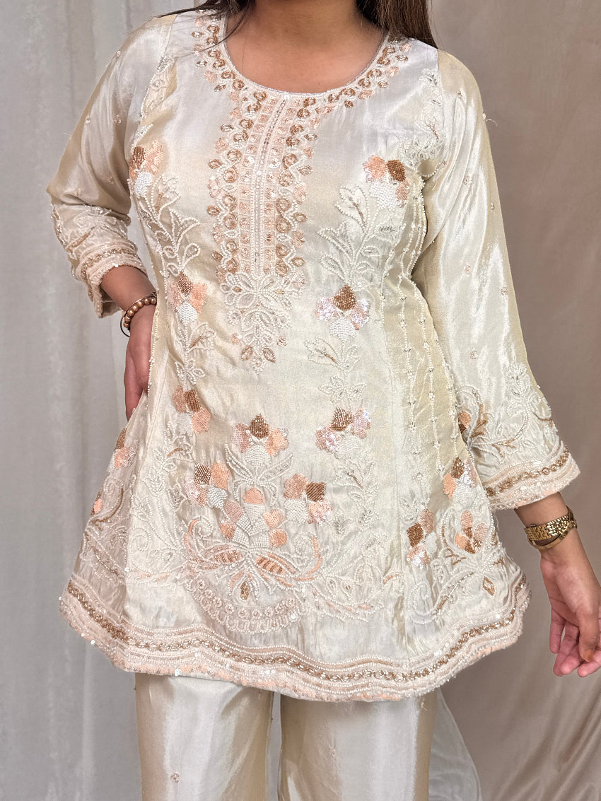 White embroidered top with floral patterns on a plain background