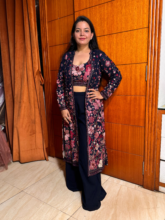 Woman wearing a floral outfit standing in front of a wooden door.
