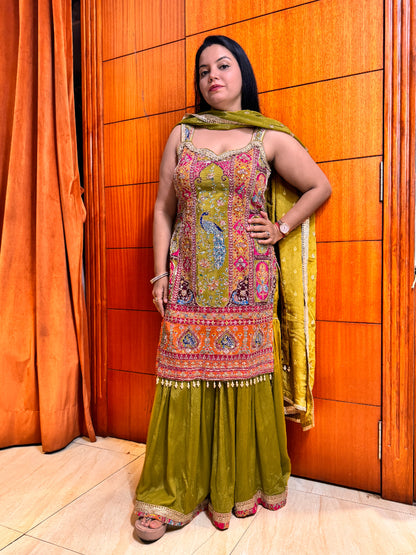Woman in a colorful traditional outfit standing against an orange wall.