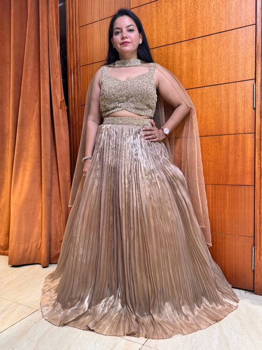 Woman in a gold traditional outfit standing against a wooden panel background
