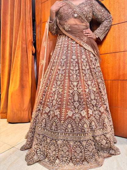 Traditional embroidered outfit with a sheer dupatta against a wooden background