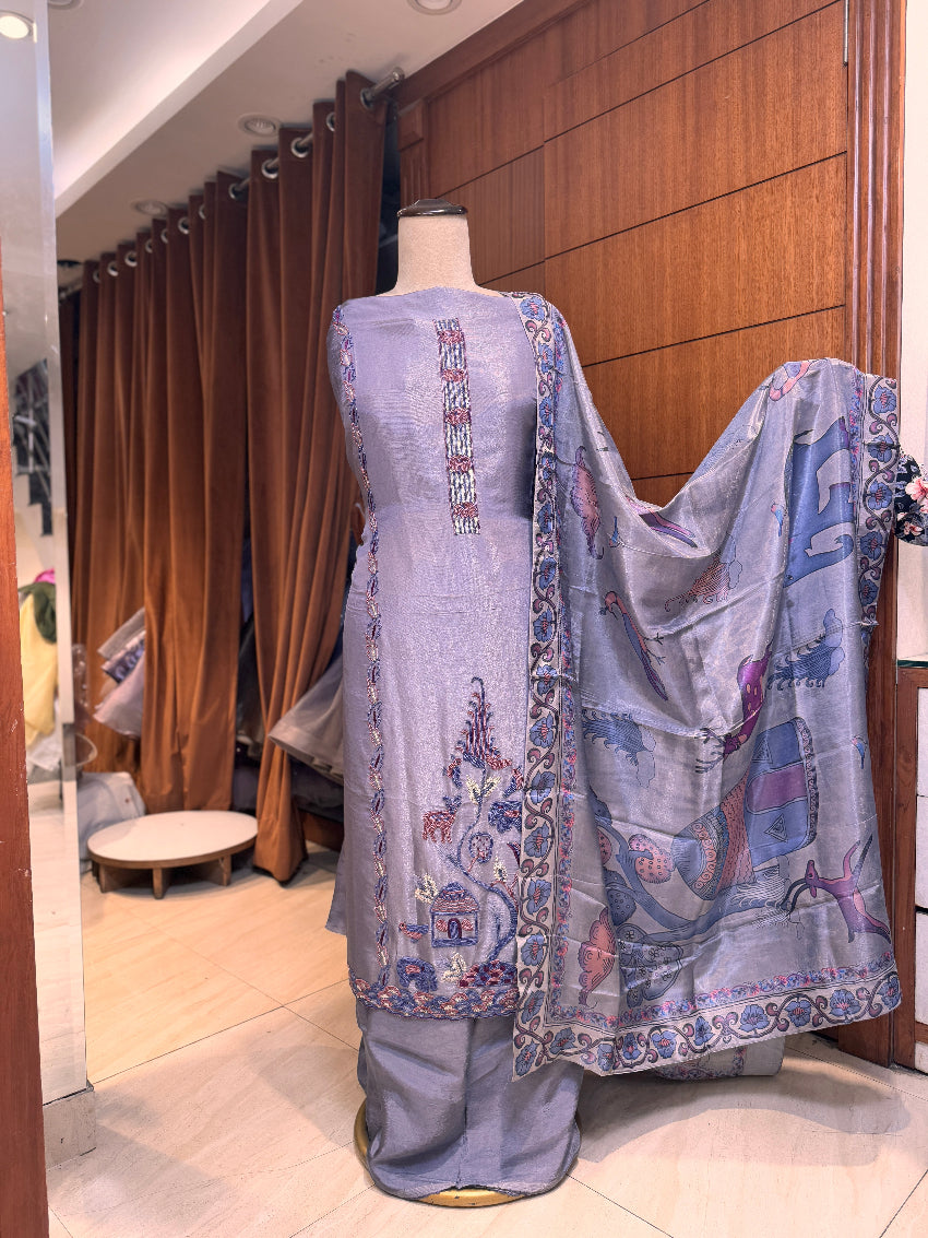 Traditional outfit with embroidered top and pants on a mannequin against a wooden panel background.