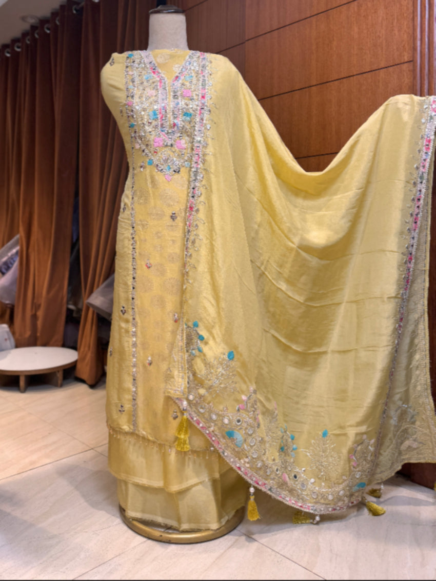 Yellow embroidered traditional outfit on a mannequin with a wooden panel background