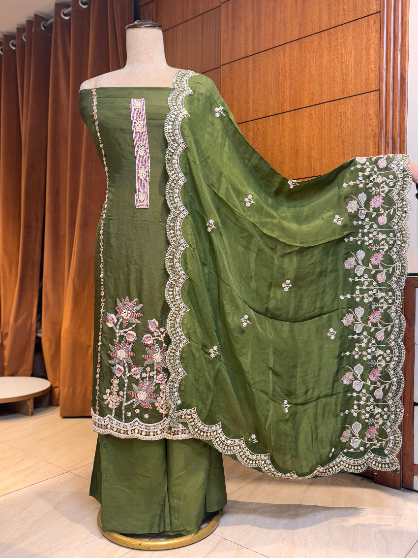 Green saree with floral embroidery on a mannequin against a wooden panel background