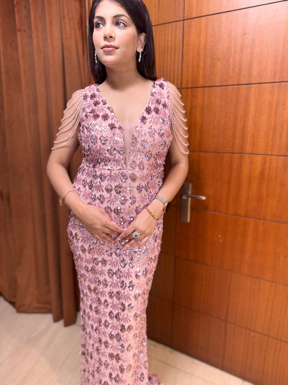 Woman in a pink floral dress standing in front of a wooden door.