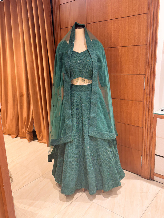 Green traditional outfit on a mannequin against a wooden panel background