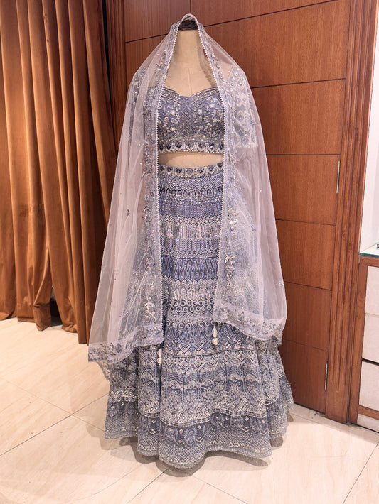 Traditional outfit with a blue and white patterned dress and matching dupatta on a mannequin against a wooden panel background.