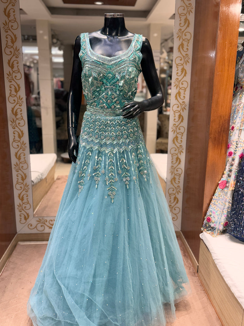 Teal evening gown with intricate beading on a mannequin in a store setting.