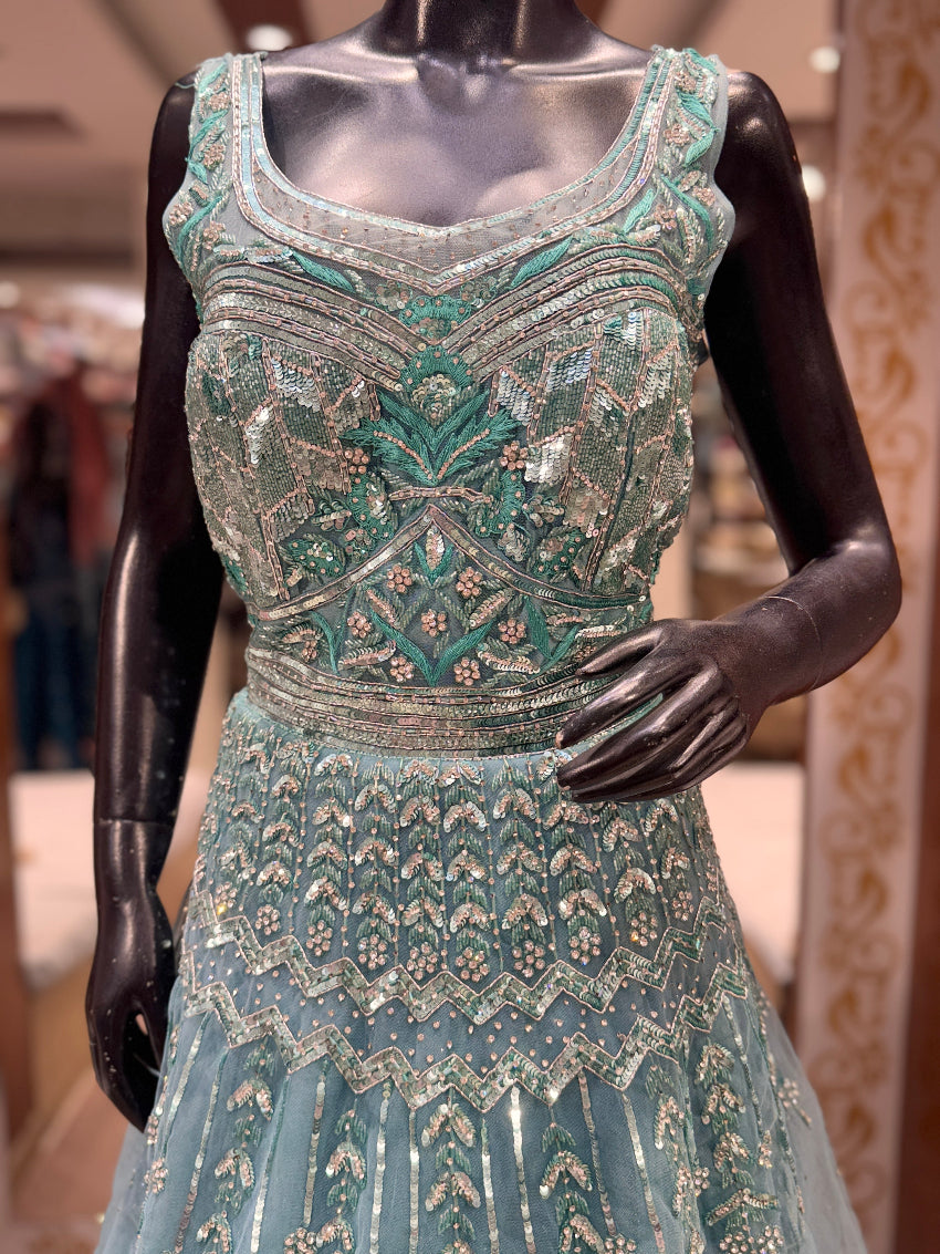 Elaborately designed green evening gown on a mannequin with a blurred indoor background