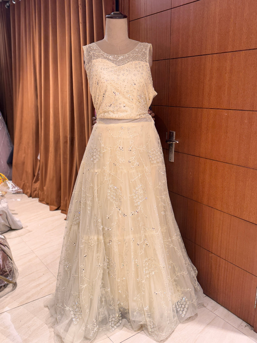 Beige embroidered evening gown on a mannequin against a wooden panel background
