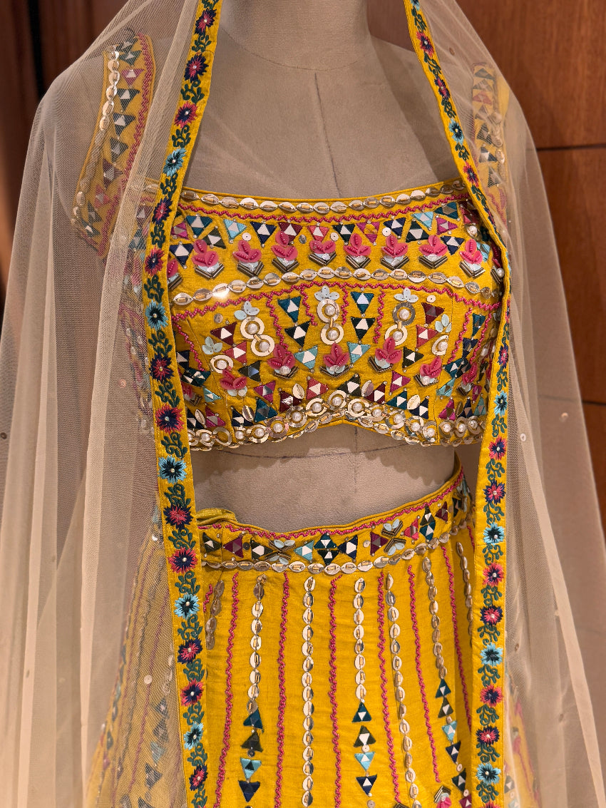Colorful embroidered traditional outfit with a sheer dupatta on a neutral background