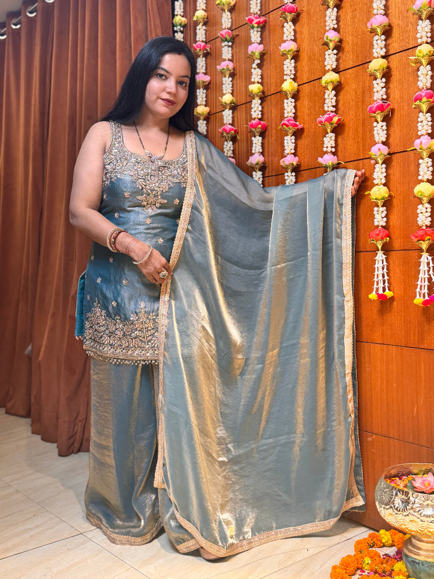 Woman in a traditional saree standing in front of a decorated wall with flowers.
