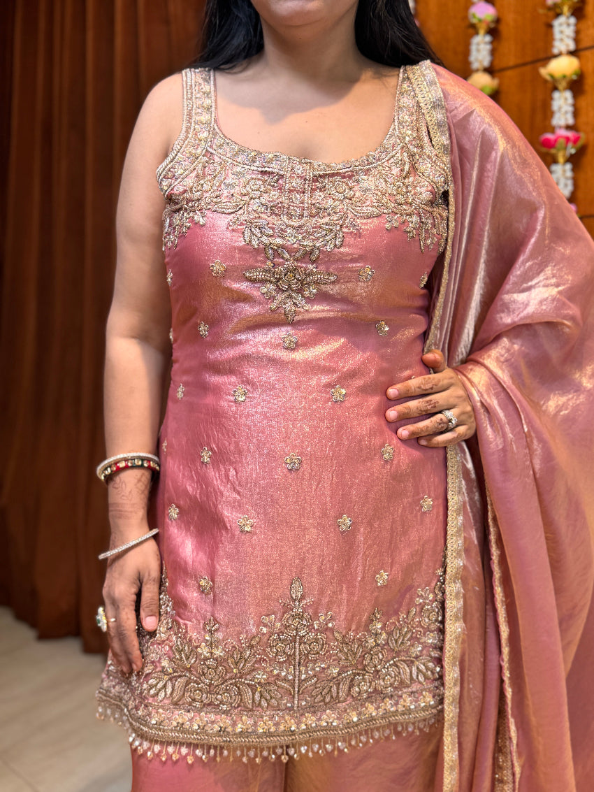Person wearing a pink embroidered traditional outfit with a dupatta.