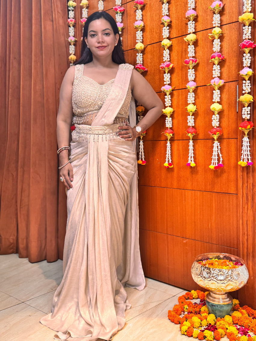 Woman in a saree standing in front of a decorated wall with garlands