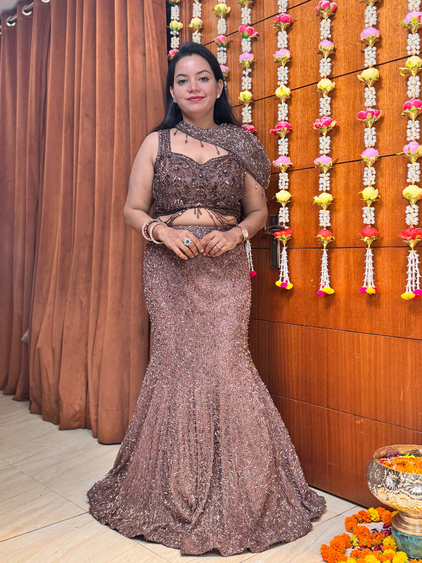 Woman in a sparkling evening gown standing in front of a decorated wall with flowers.