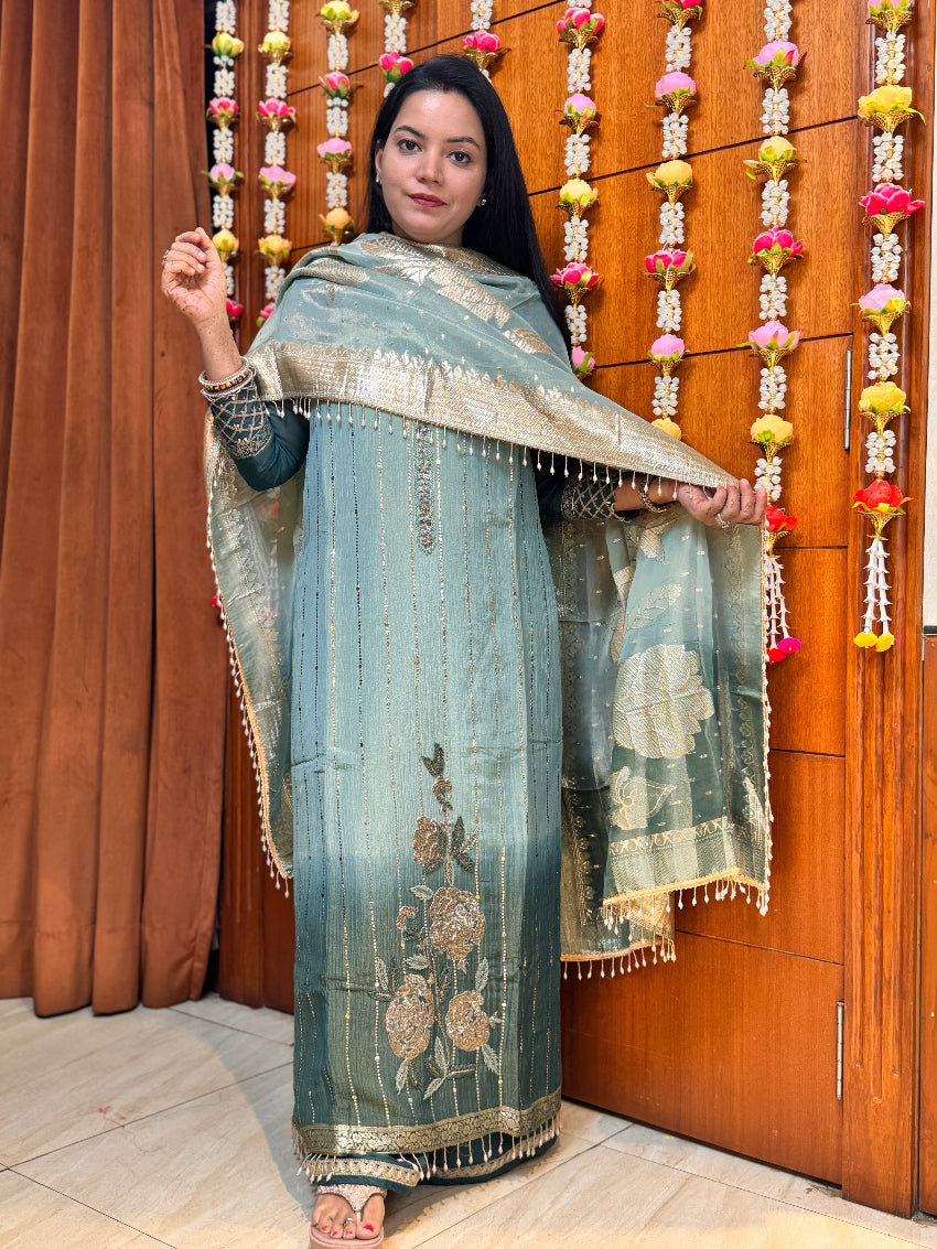 Woman holding a traditional embroidered shawl against a wooden background with decorative elements.