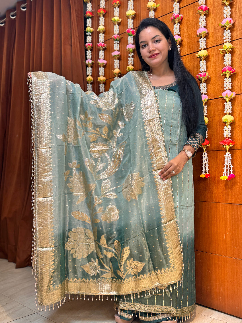 Woman holding a traditional embroidered saree in a decorated indoor setting