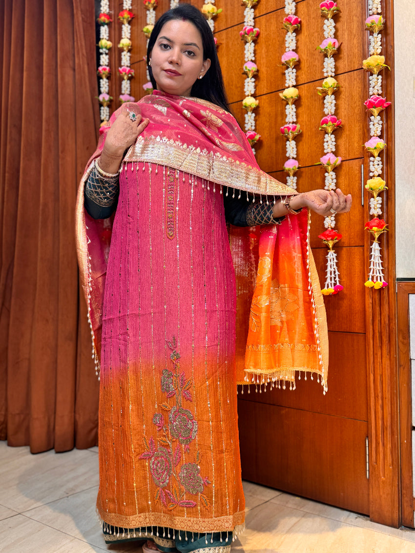 Woman holding a pink and orange embroidered dupatta against a wooden background