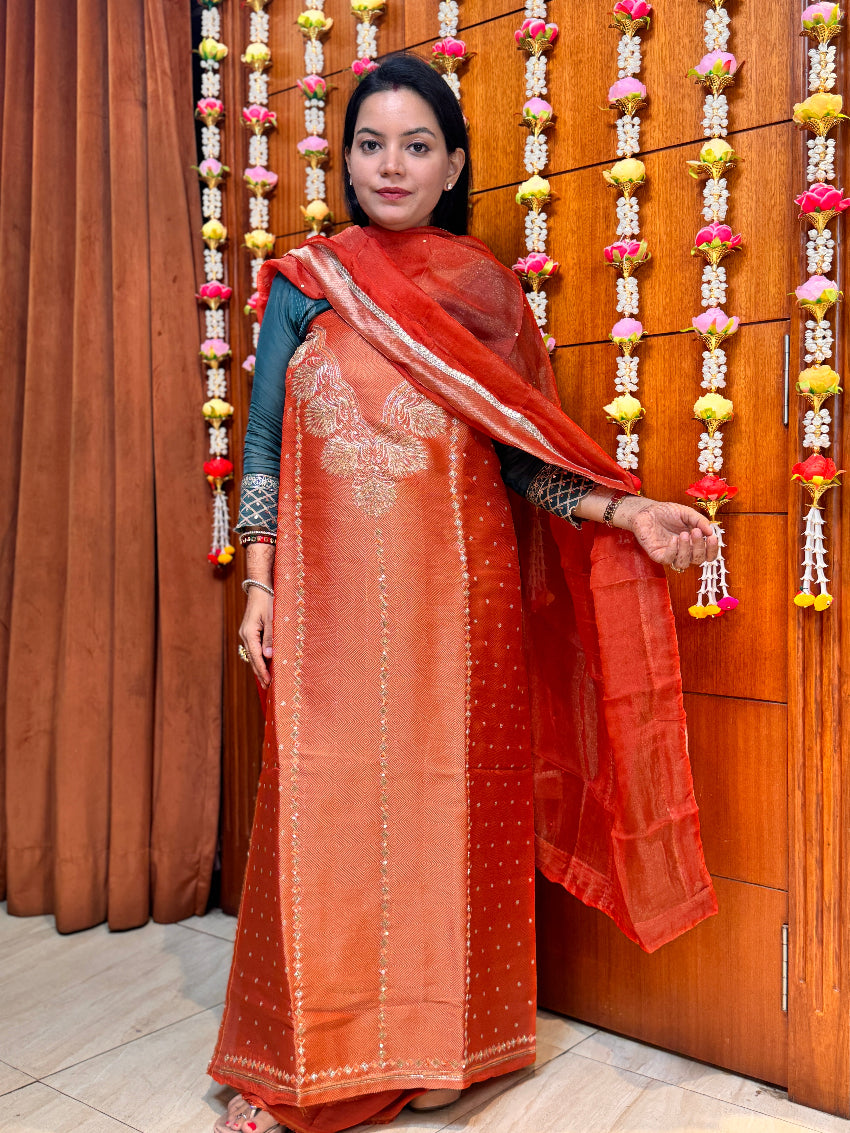 Woman in traditional attire standing in front of a decorative wall with hanging garlands.