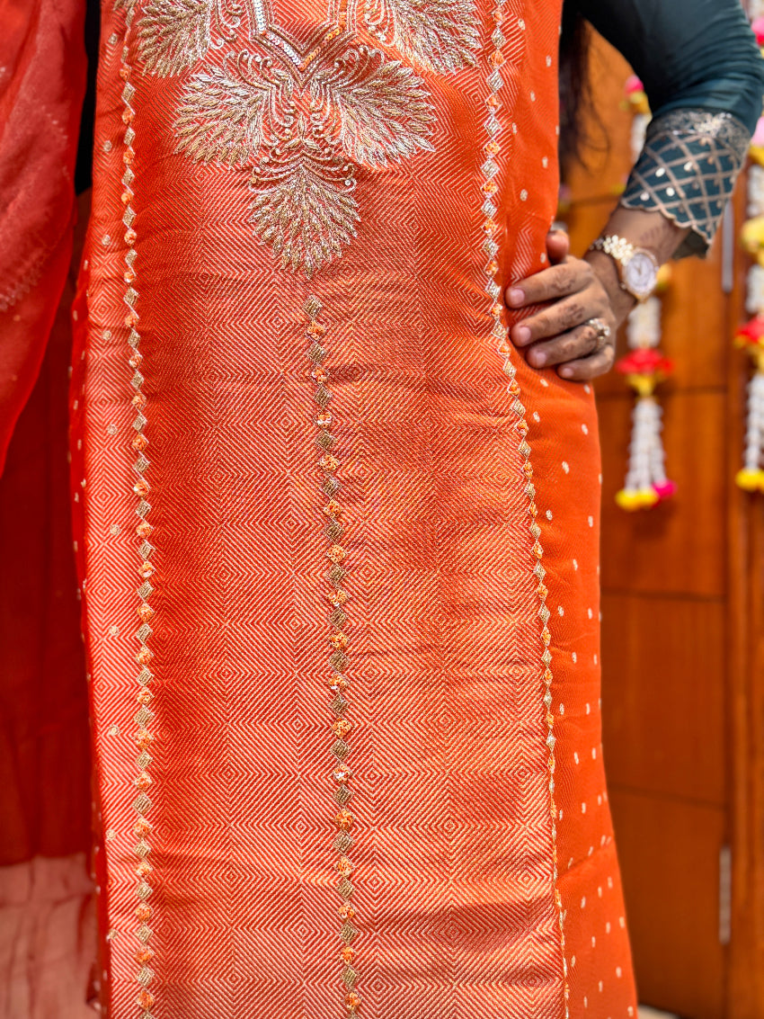 Close-up of an orange embroidered fabric with intricate patterns.