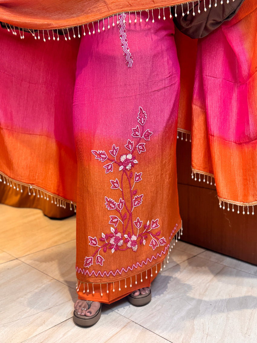 Person wearing a traditional saree with floral embroidery on a wooden floor.