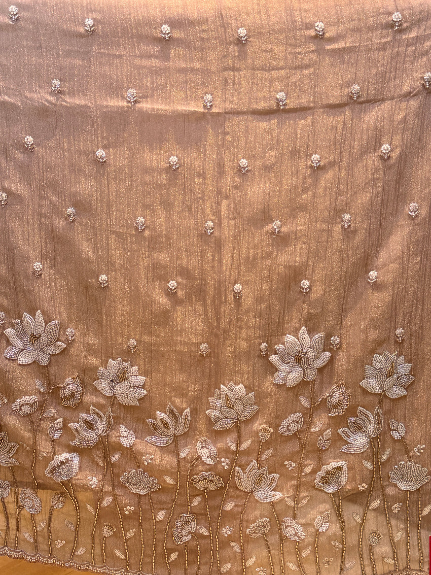 Close-up of a brown fabric with floral embroidery and beadwork