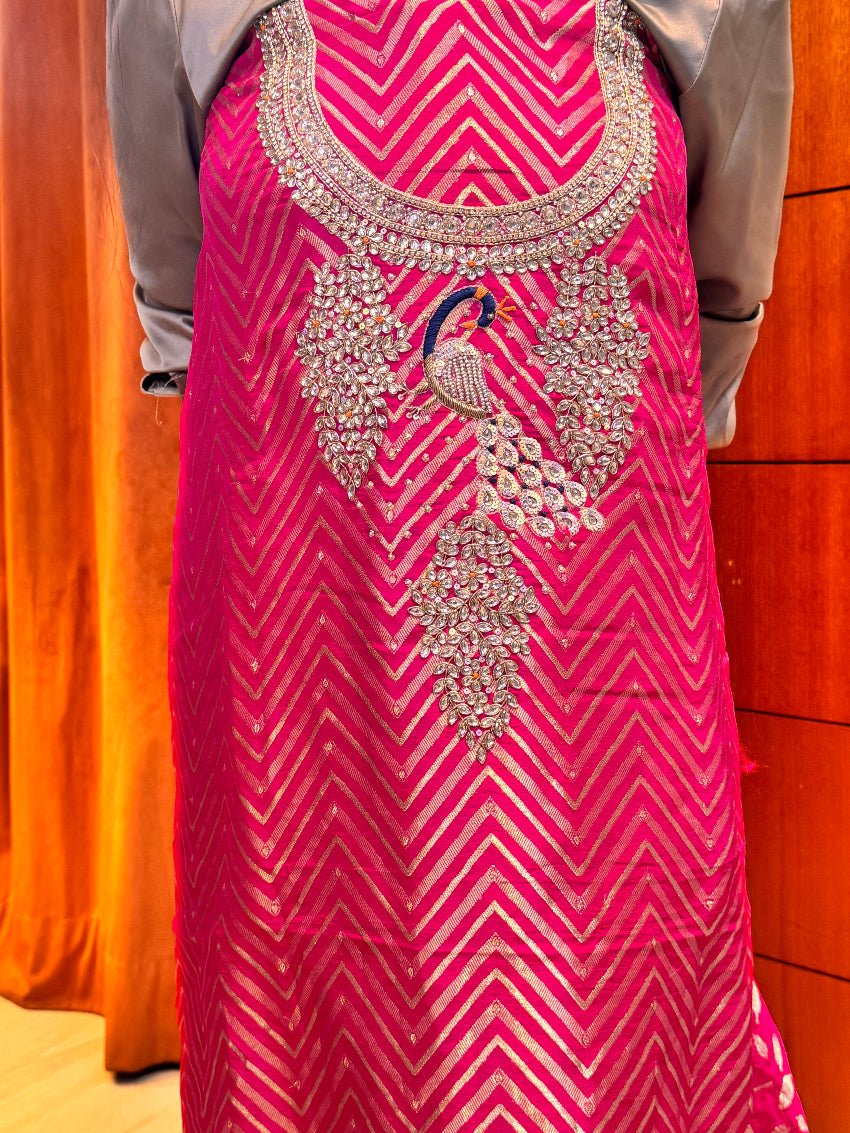 Pink fabric with intricate silver embroidery on a wooden surface